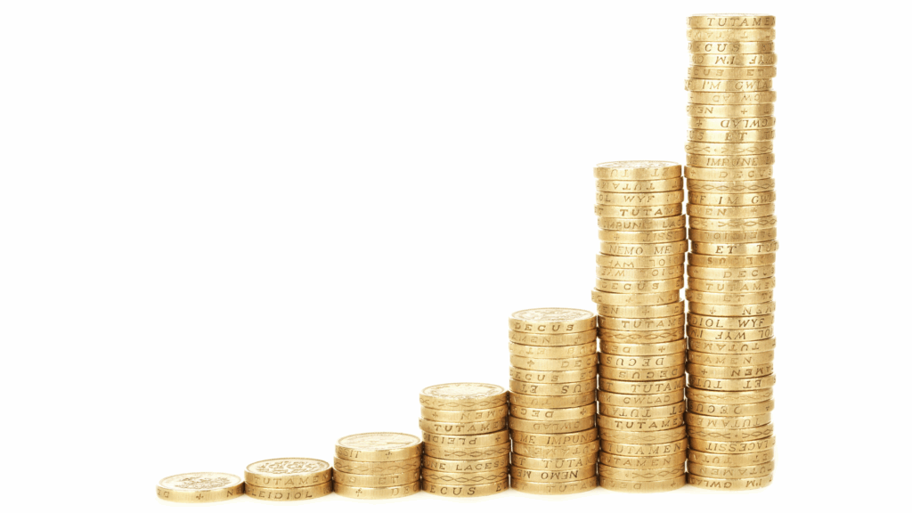 A visual representation of financial growth is shown with seven stacks of gold-colored coins arranged in a rising bar graph, with the shortest stack on the left and the tallest on the right.